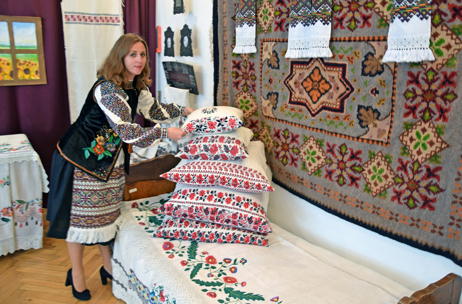 Леся Сута, старший науковий працівник краєзнавчого музею, поправляє вишиті подушки, які в західноукраїнській хаті прикрашали ліжко. Фото автора